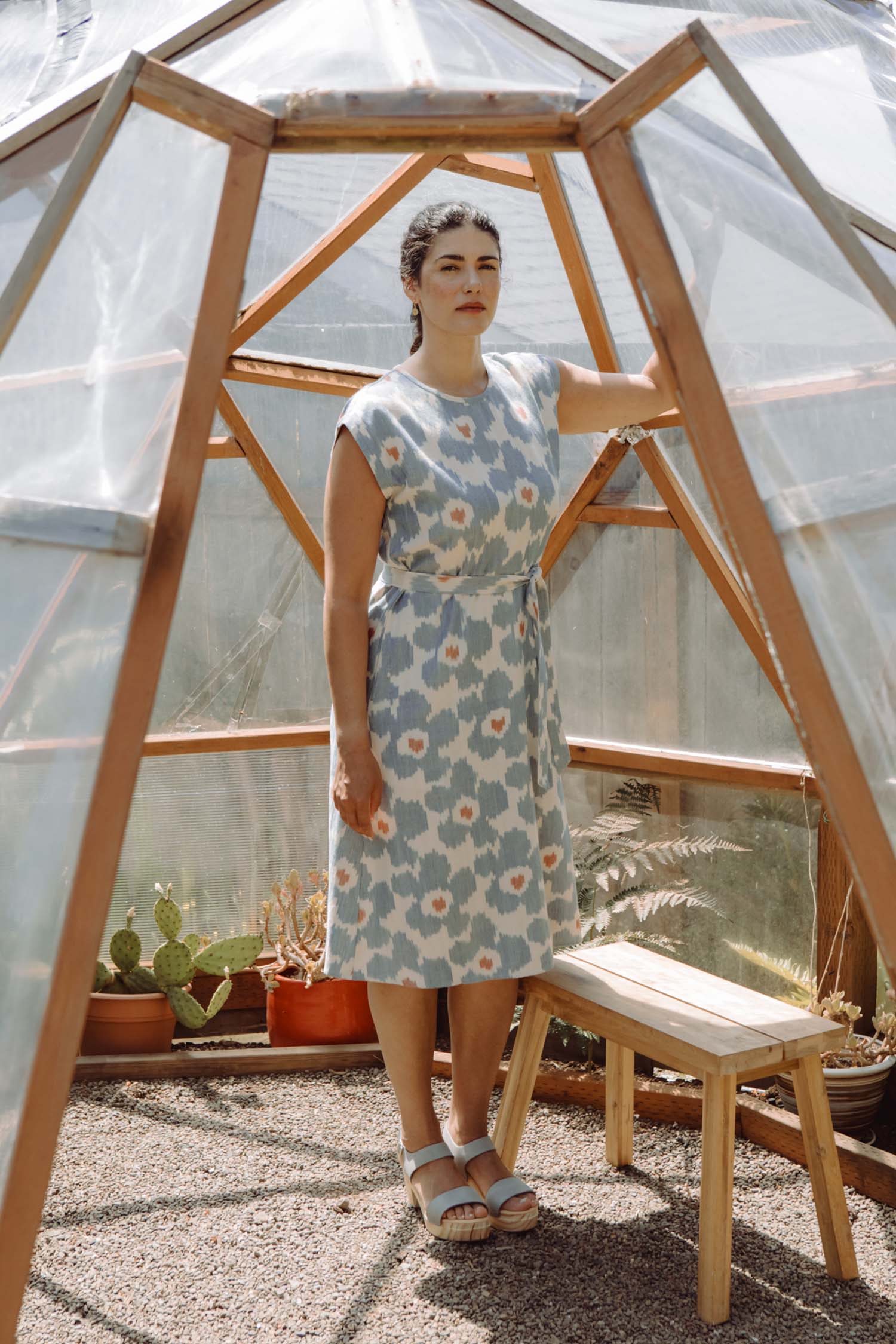 The Eloise Dress / Polar Blossom by Bridge & Burn is a short-sleeve, knee-length A-line dress featuring a blue and white abstract print with orange accents, a round neckline, matching fabric belt, and is shown laid flat on white.