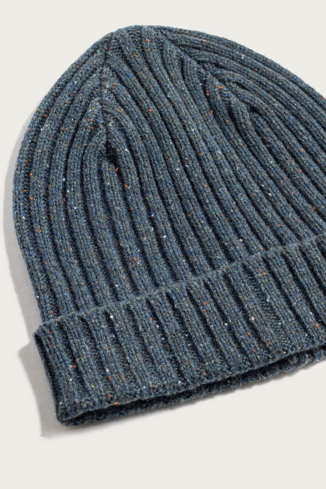 A close-up of the Bridge & Burn Chunky Ribbed Beanie / Seaside, featuring a blue ribbed knit with a folded brim and subtle orange and beige flecks, displayed on a light background.