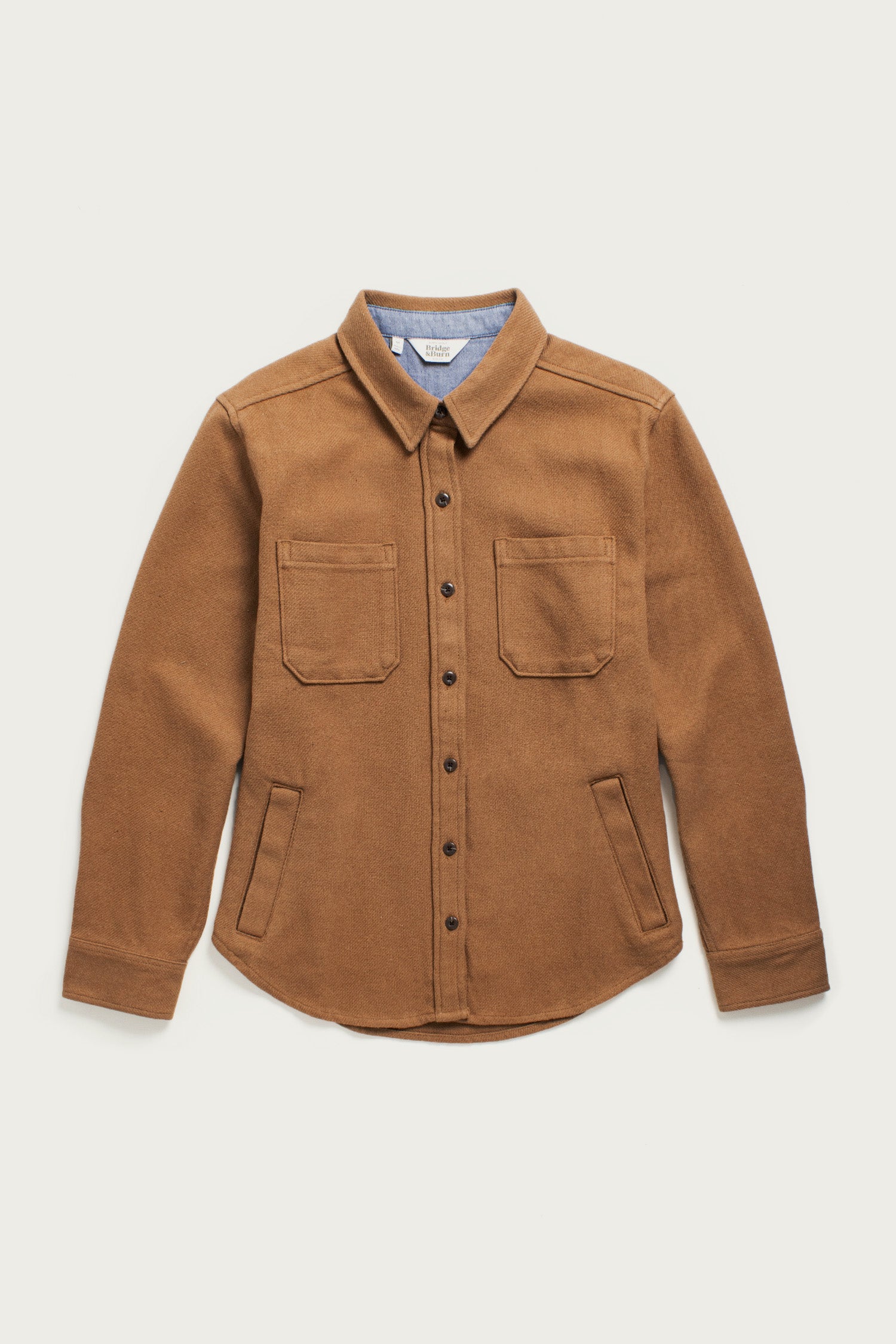 The Bridge & Burn Dawson Overshirt in Camel features a pointed collar, two chest pockets, long sleeves, and a rounded hem. Made from recycled cotton, this heavyweight overshirt is shown flat on a white background.