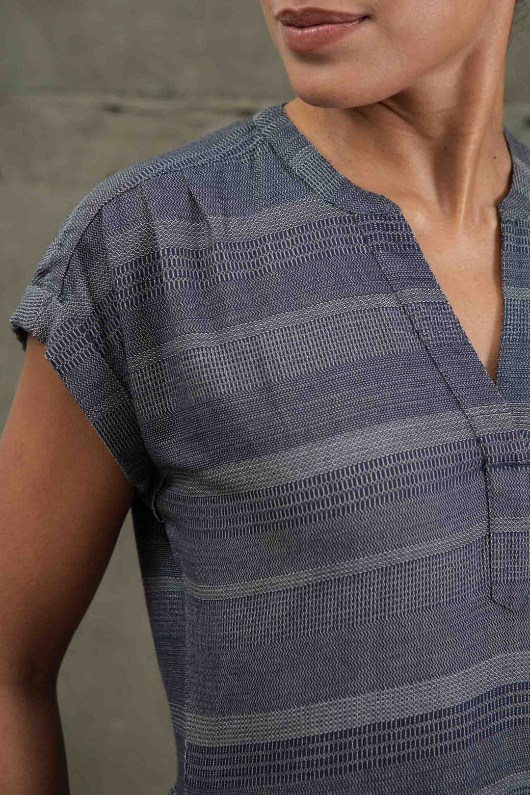 A person wearing the Bridge & Burn Ira Dress in Cascade Weave—a short-sleeved, blue and gray striped pullover with a textured pattern and V-neckline—shown from shoulders to mid-torso against a plain background.