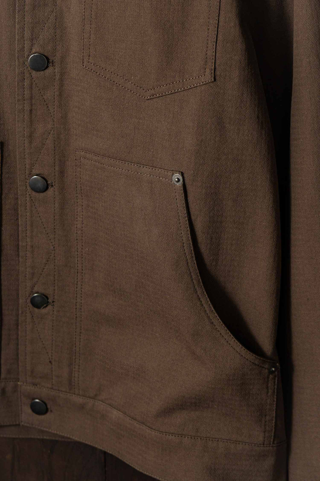 Close-up of the Bridge & Burn Burl Trucker Jacket in Walnut, featuring black snap buttons, a stitched chest pocket, and a large side pocket with metal rivet. The sturdy fabric gives this workwear classic a durable look.