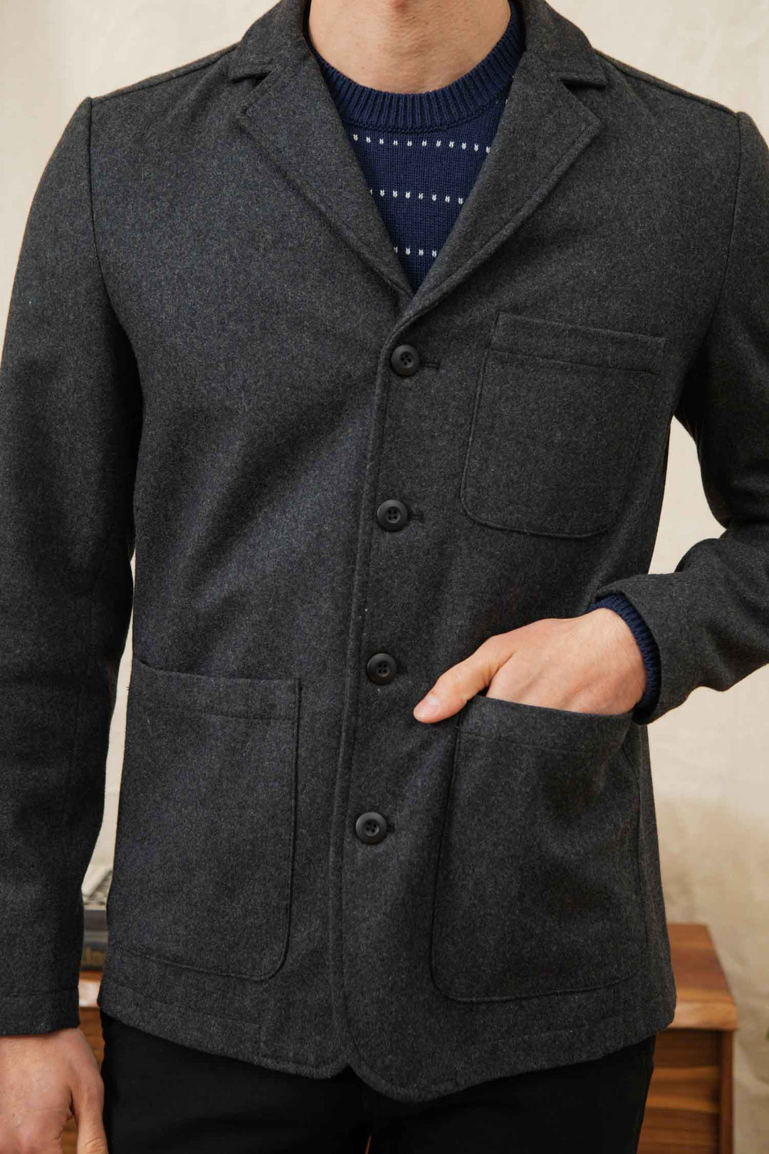 A person wears the Bridge & Burn Nate Chore Blazer in Onyx Wool over a navy blue sweater with a white dotted pattern—an ideal winter piece.