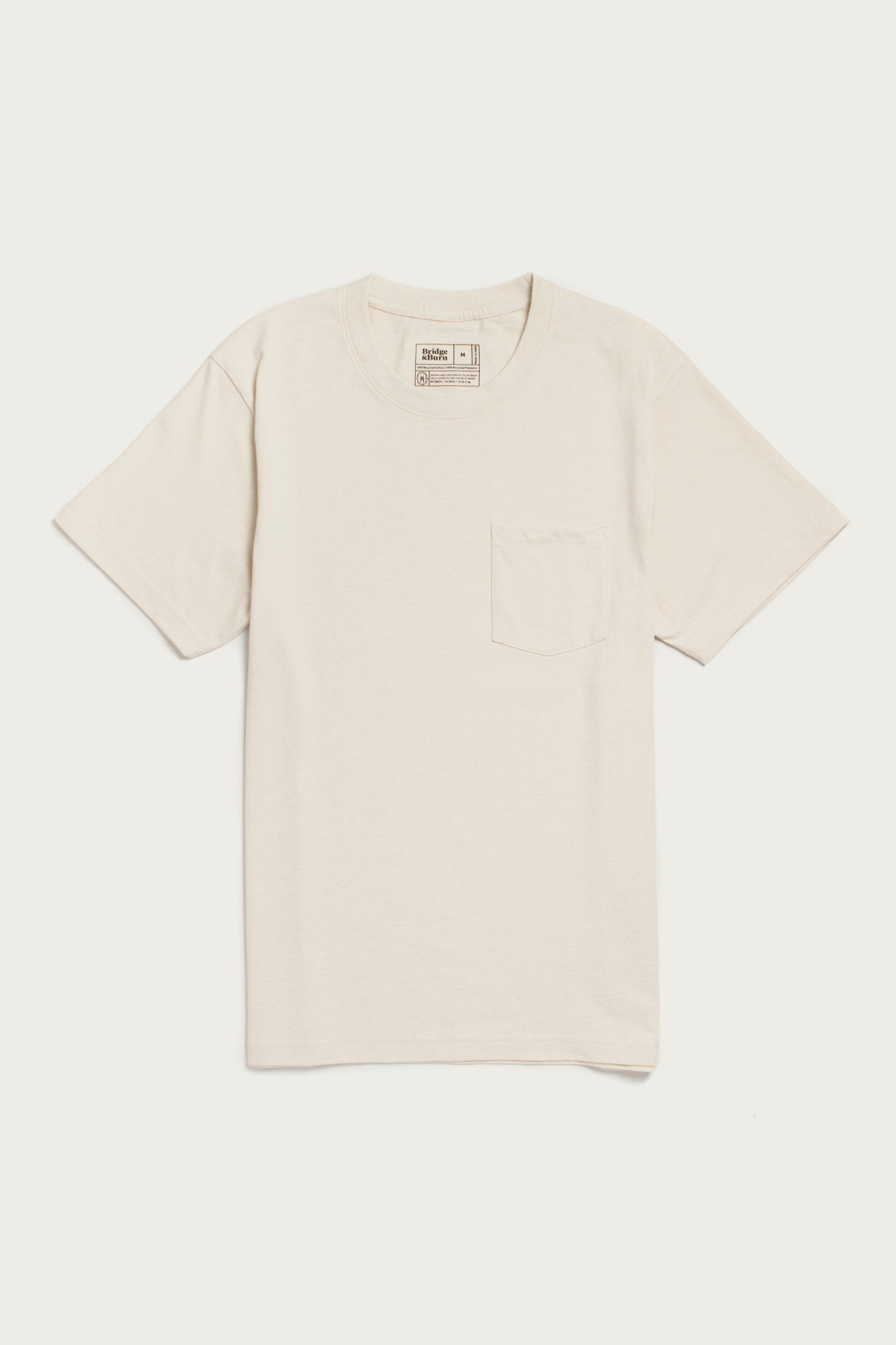 The Bridge & Burn Recycled Pocket Tee in Ivory is a sustainable, short-sleeve crewneck made from recycled cotton, featuring a left chest pocket and shown on a white background.
