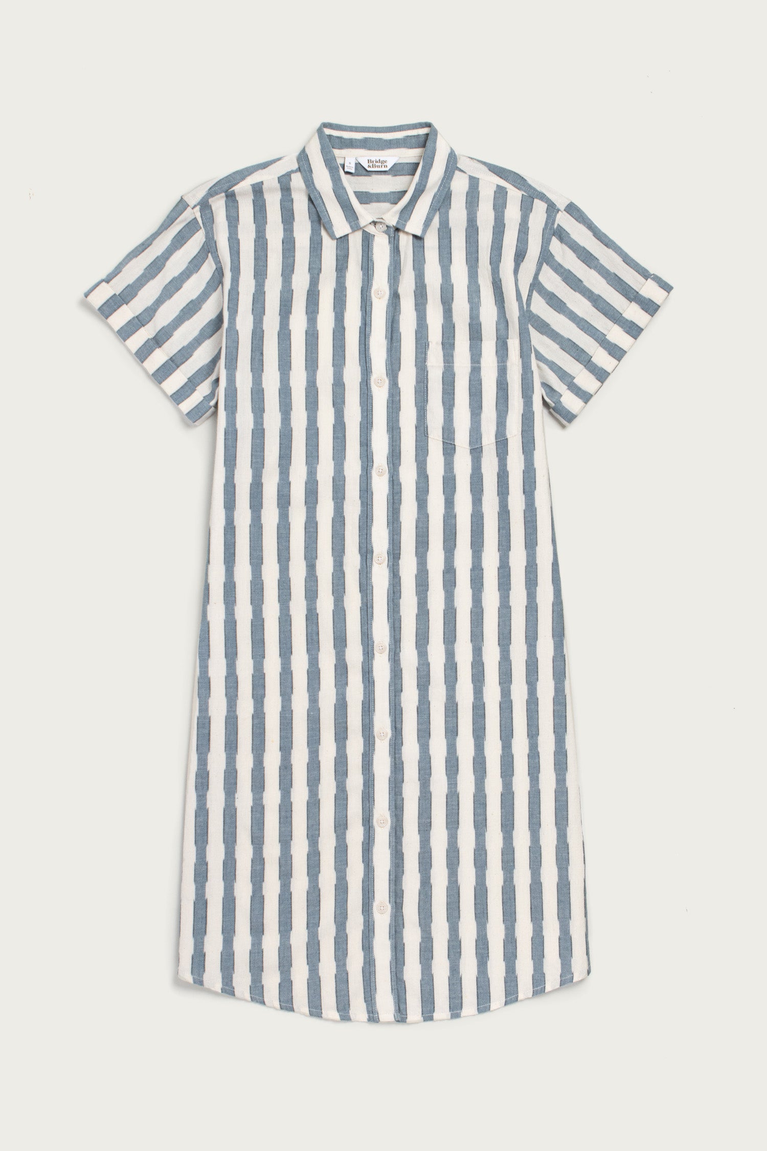 Bridge & Burn's Loren Shirt Dress in Beach Stripe features blue and white vertical stripes, a button front, short sleeves, collar, and is made from 100% cotton. Knee-length style—perfect for work or lounging. Shown laid flat on white.