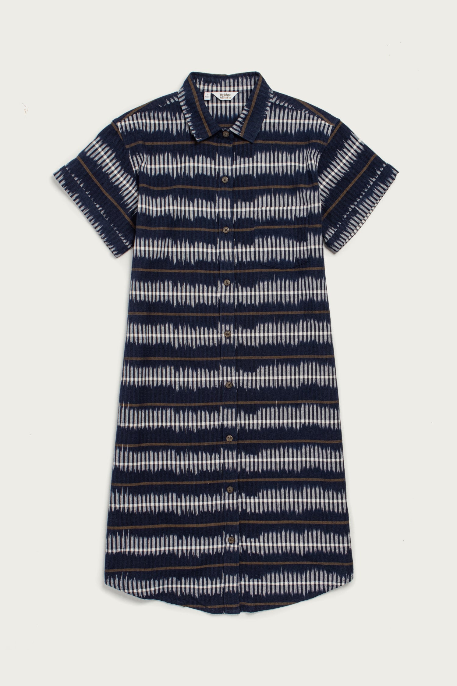 The Loren Shirt Dress by Bridge & Burn features a short-sleeve, button front design with a collar in a navy and white striped pattern. Made from 100% cotton, this relaxed-fit work dress ensures all-day comfort.