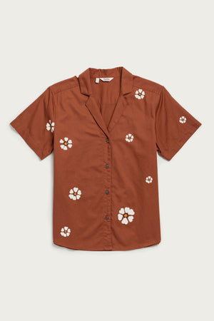 The Wren Shirt by Bridge & Burn in Redstone Bloom is a breathable cotton, short-sleeved button-up with a notched collar and scattered white and yellow floral prints for a relaxed fit.
