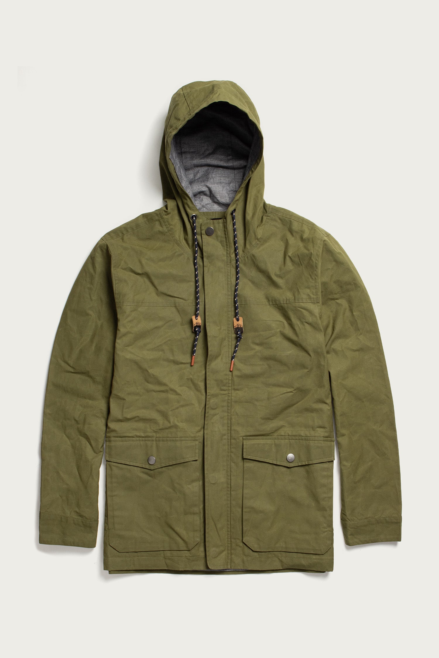 The Bridge & Burn Marshall Jacket in olive waxed canvas features water-resistant British Millerain fabric, a hood with black and white drawstrings and brown accents, front flap pockets, snap buttons, and zip closure.