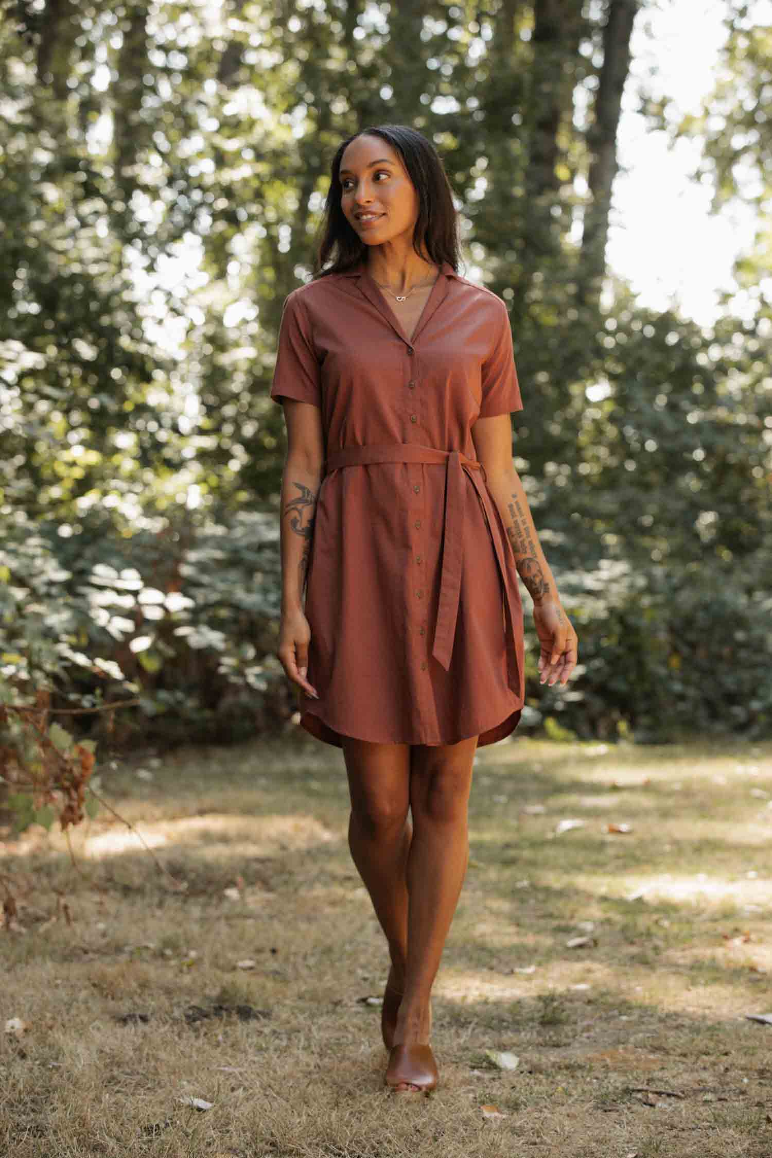 The Bridge & Burn Sofia Shirt Dress in Copper is a lightweight, short-sleeved button-front dress with a collar and matching fabric belt, crafted from rust-brown organic cotton and shown laid flat on a light background.