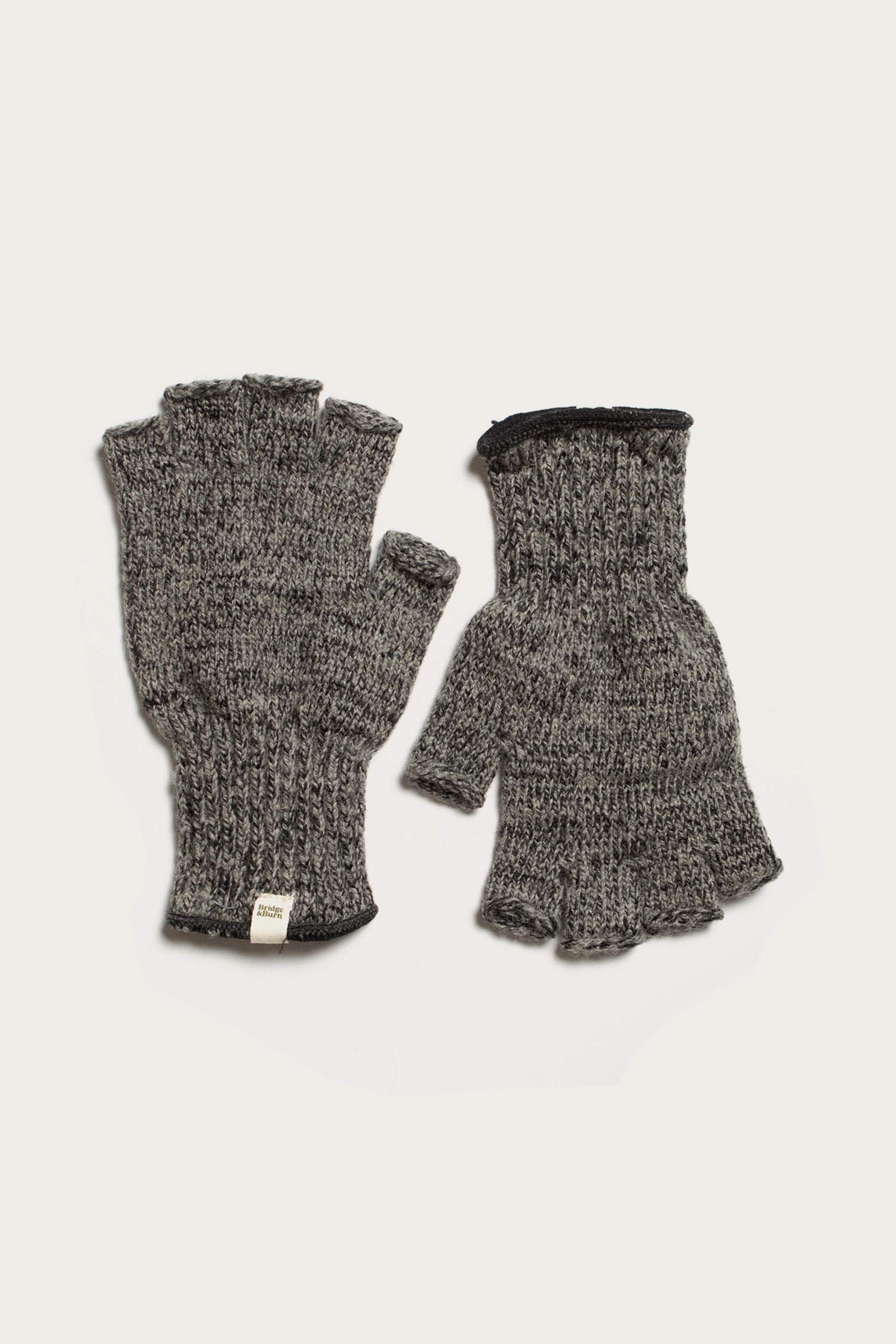 Bridge & Burn's Ragg Wool Fingerless Glove in Charcoal features a ribbed texture and a small white tag near the wrist. Shown on a white background, these cozy gloves keep your hands warm while leaving your fingers free.