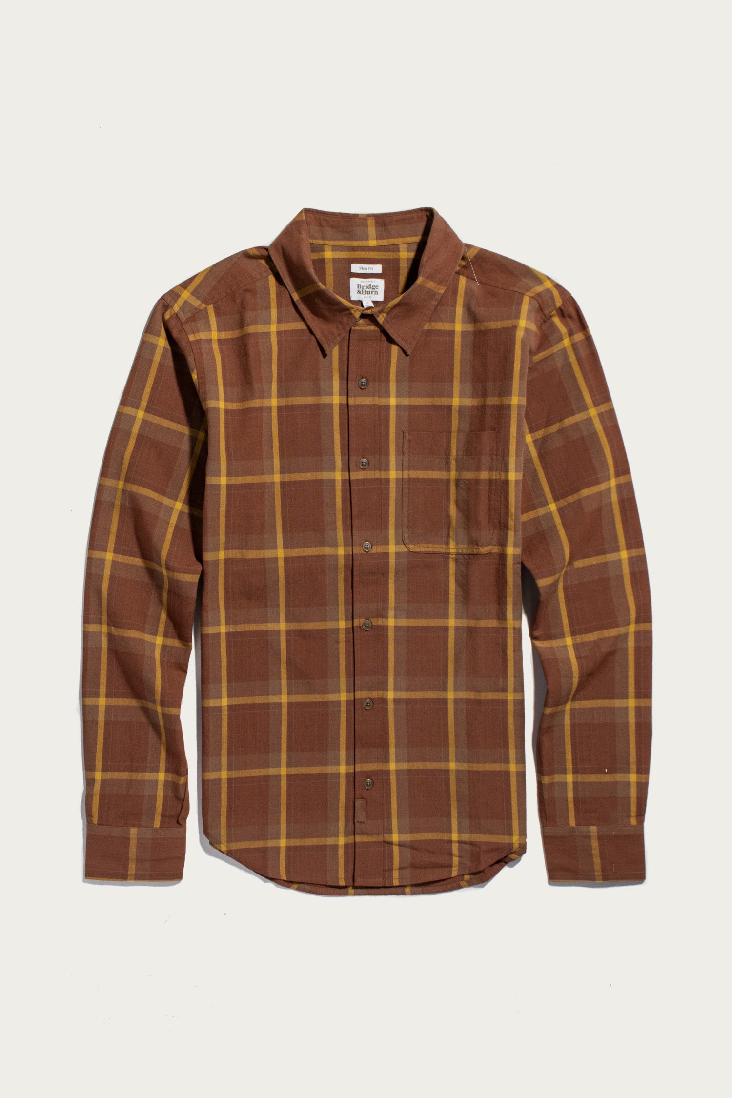 The Larson Shirt in Harvest Plaid by Bridge & Burn is a long-sleeve, classic fit button-up crafted from organic cotton, featuring a brown and yellow brushed flannel plaid pattern with a chest pocket. The shirt is shown laid flat against a white background.