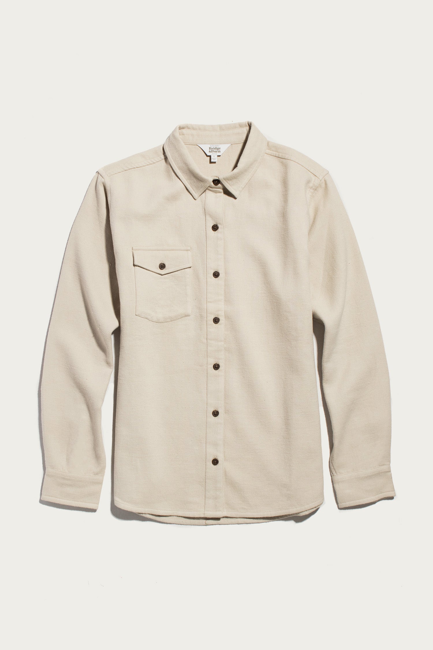 A Bridge & Burn Bird Shirt in Fawn Flannel, featuring a collared neckline, long sleeves, button-up front, and a single chest pocket, made from organic cotton flannel in a relaxed fit, is laid flat on a white background.