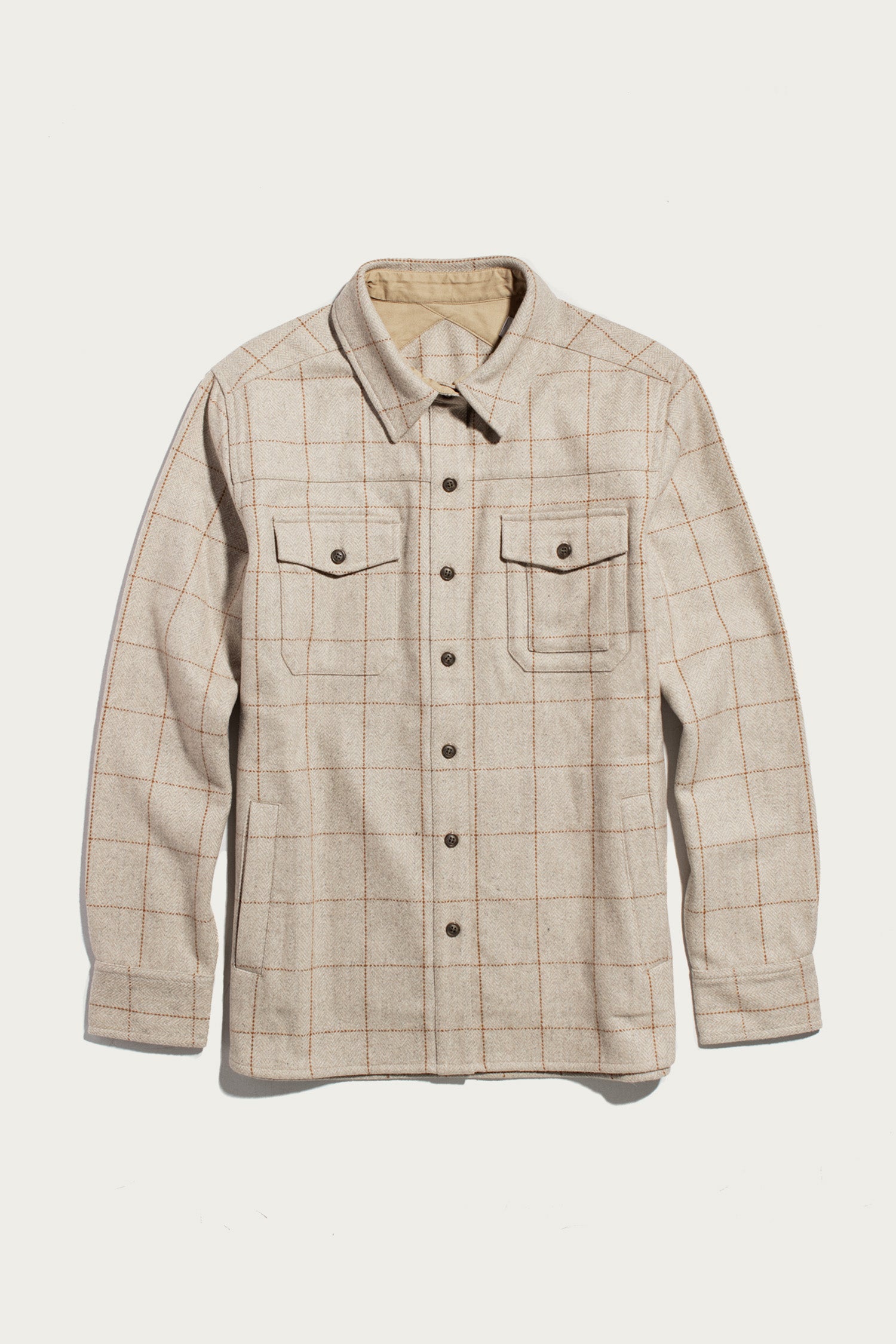 The Bridge & Burn Harlow Shirt Jacket in Stonecross is a beige long-sleeve wool shirt jacket with a light brown windowpane plaid, workwear-style elbow patches, chest pockets with button flaps, and a pointed collar, shown flat on a white background.