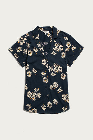The Bridge & Burn Innes Shirt in Night Garden is a relaxed-fit, short sleeve, button-up shirt with a dark navy base and white-yellow floral pattern, crafted from organic cotton. Displayed flat on a white surface.