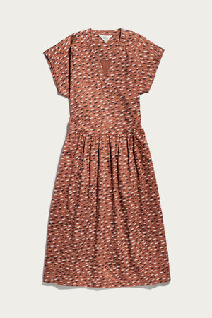 The Ira Dress / Desert Rain by Bridge & Burn is a rust midi pullover with short dolman sleeves, v-neckline, gathered waist, and an abstract white and black dash pattern.