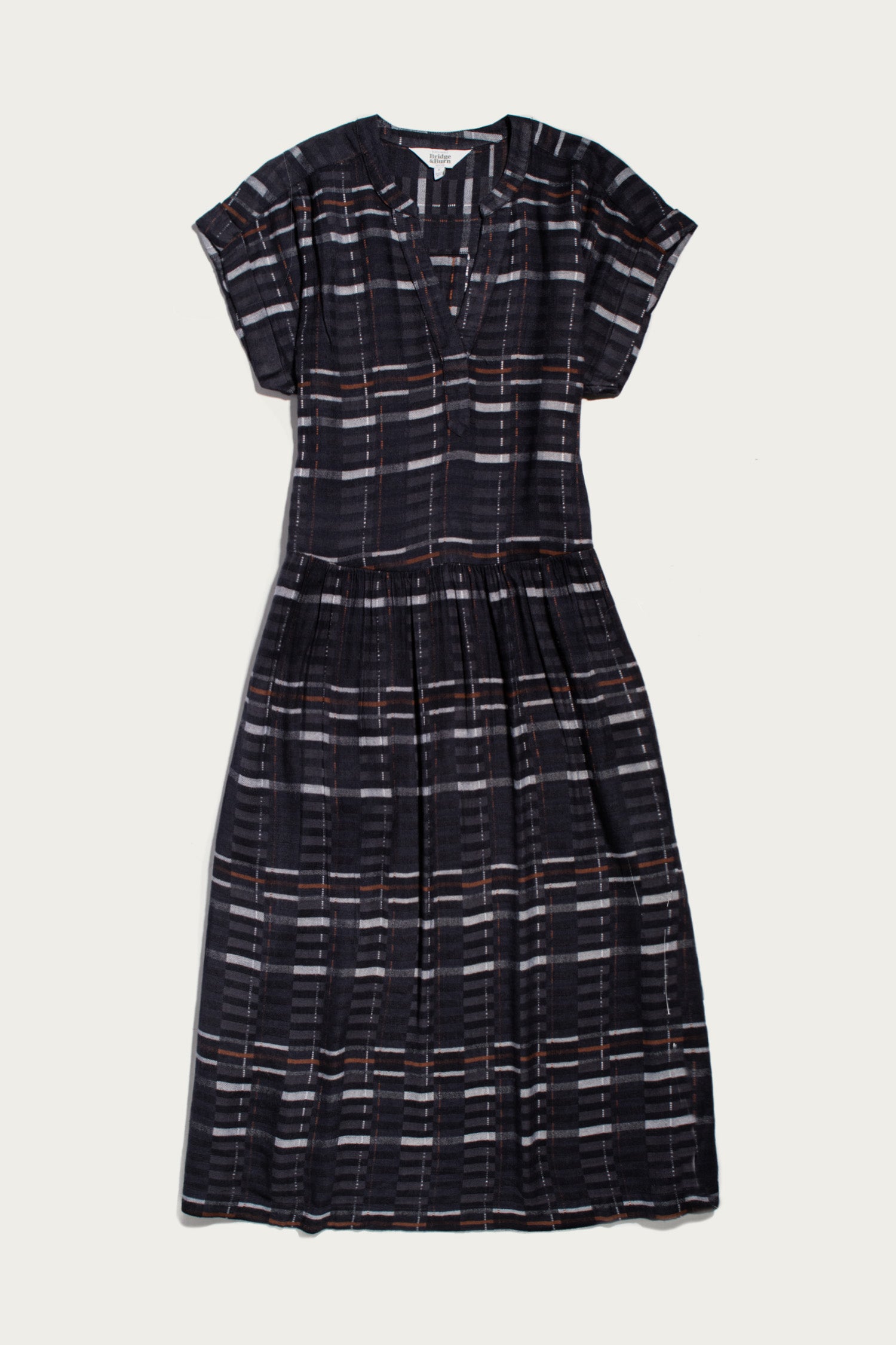 The Ira Dress by Bridge & Burn features short sleeves, a knee-length pullover design in Nightfall Stripe, with a V-neck, subtle waist pleats, and a relaxed fit.
