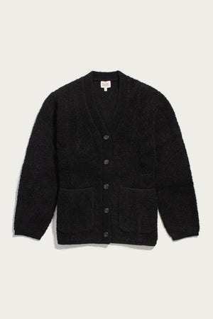 Whit Cardigan by Bridge & Burn in black, featuring a long-sleeve V-neck button-up design with two front pockets, shown flat on a white background. The textured knit fabric looks soft and inviting.