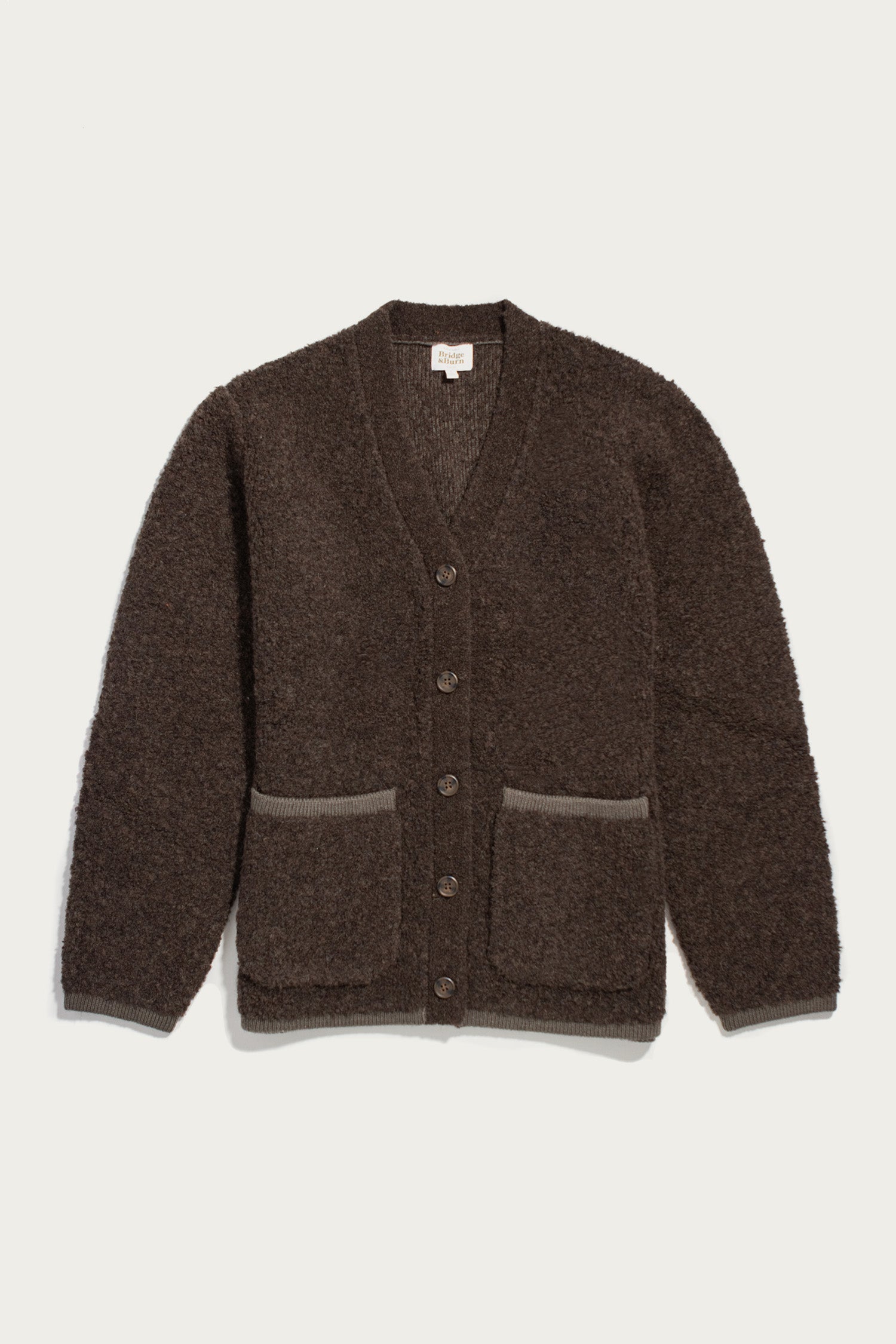 The Bridge & Burn Whit Cardigan in dark olive is a textured wool-blend sweater with long sleeves, V-neck, button front, two pockets, and light brown trim. Machine wash or dry clean. Shown laid flat on a white background.