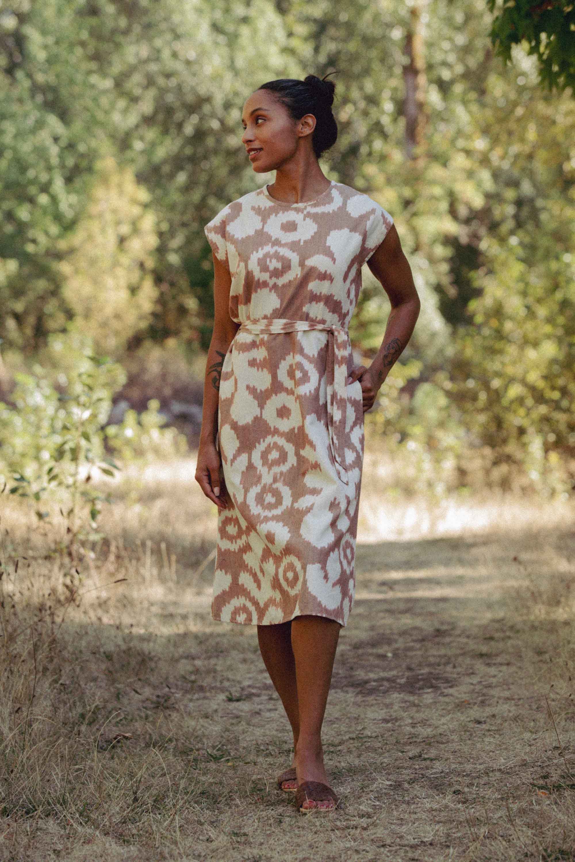 The Eloise Dress in Pop Leaf by Bridge & Burn features a sleeveless A-line cut, round neckline, abstract beige and white print, and a matching fabric belt—an essential piece for any wardrobe.