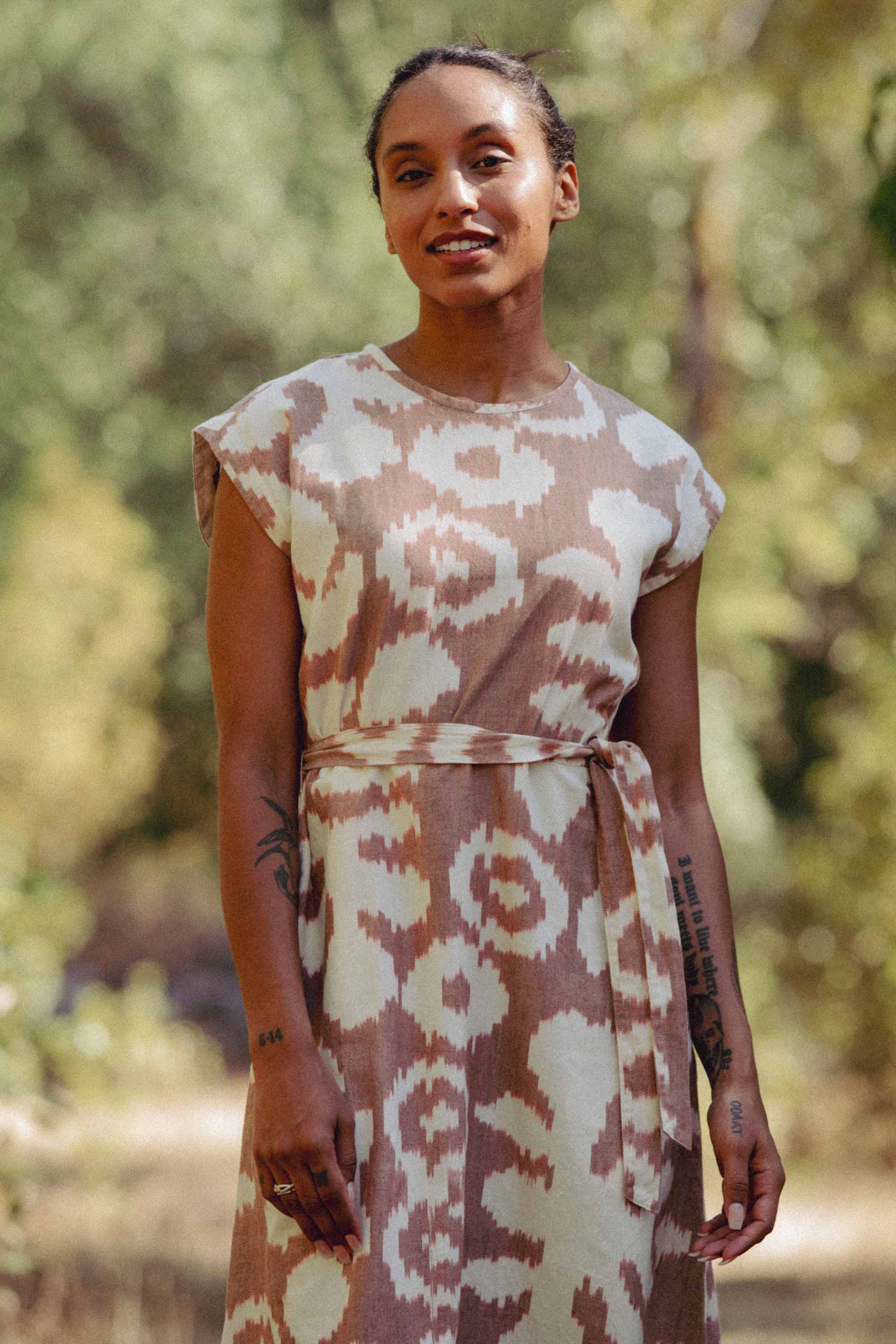 The Eloise Dress in Pop Leaf by Bridge & Burn features a sleeveless A-line cut, round neckline, abstract beige and white print, and a matching fabric belt—an essential piece for any wardrobe.