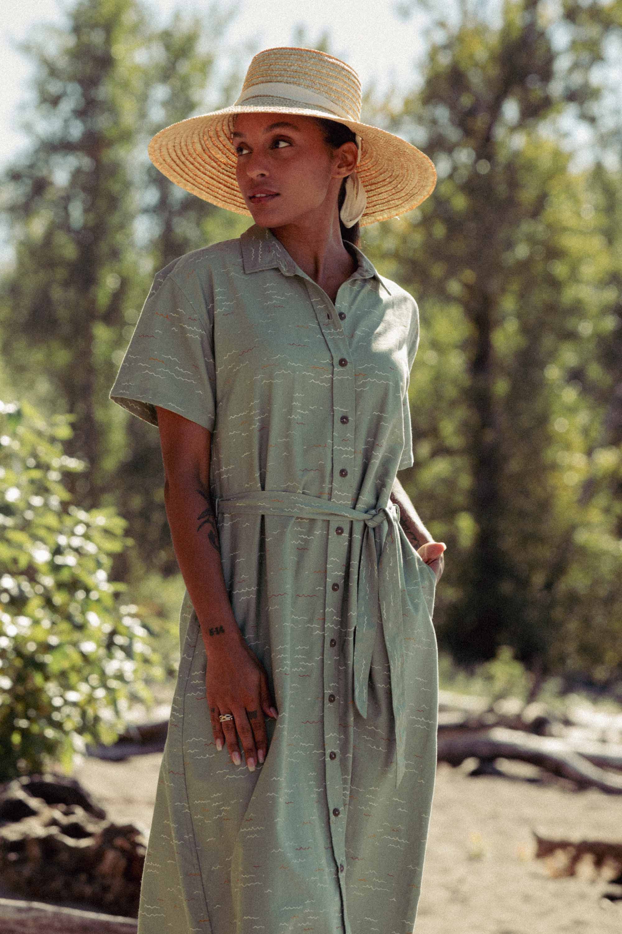 The Bridge & Burn Sylvie Dress in Teal Tide Waves is a light green, short-sleeve, collared shirtdress with a matching belt and subtle abstract print. Made from organic cotton, this relaxed midi dress is shown flat on a light background.