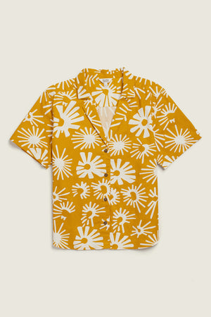 The Mila Cropped Shirt / Solar Bloom by Bridge & Burn is a short-sleeved, button-up mustard yellow shirt with a white abstract starburst print, crafted from organic cotton for a relaxed fit and effortless comfort.
