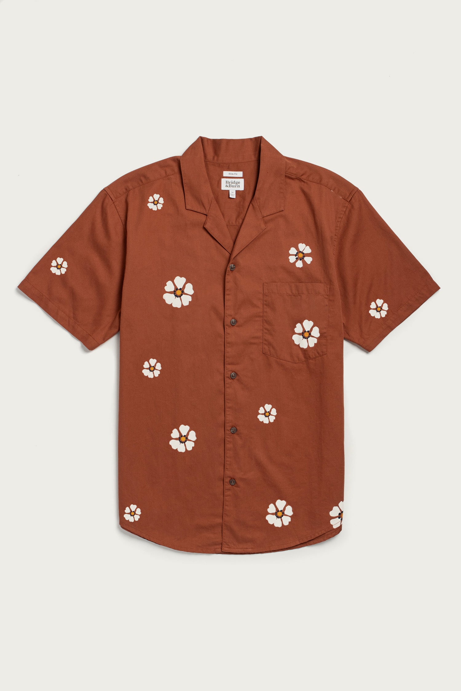 The Collins Slim Shirt by Bridge & Burn features short sleeves, a button-up front, camp collar, and chest pocket. Made from summerweight cotton, it showcases the Redstone Bloom print with scattered white and yellow florals.