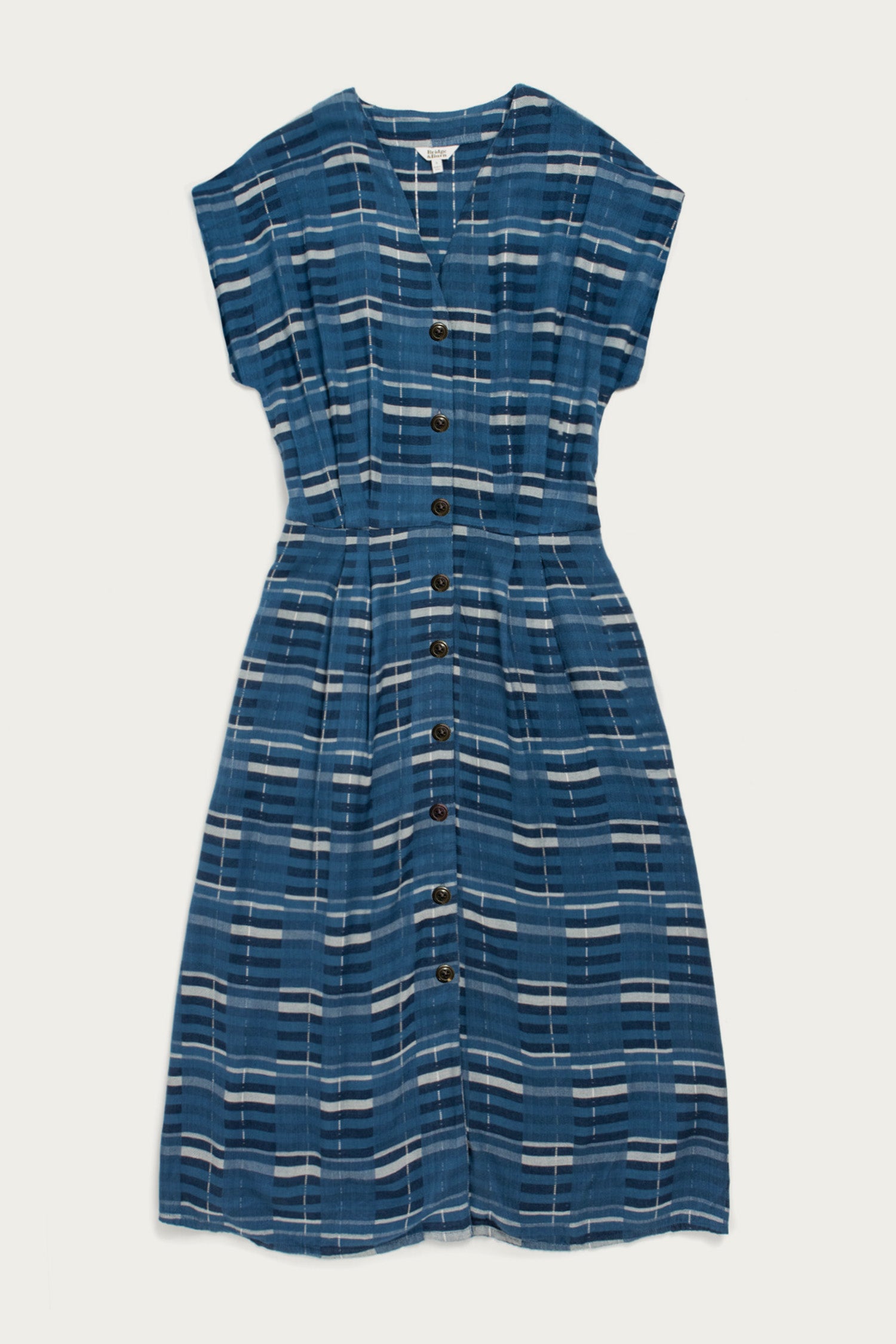 The Eileen Dress by Bridge & Burn in Stormcrest Stripe is a blue fit-and-flare with short sleeves, knee-length A-line skirt, white and navy plaid pattern, front buttons, V-neckline, and a slightly gathered waist.