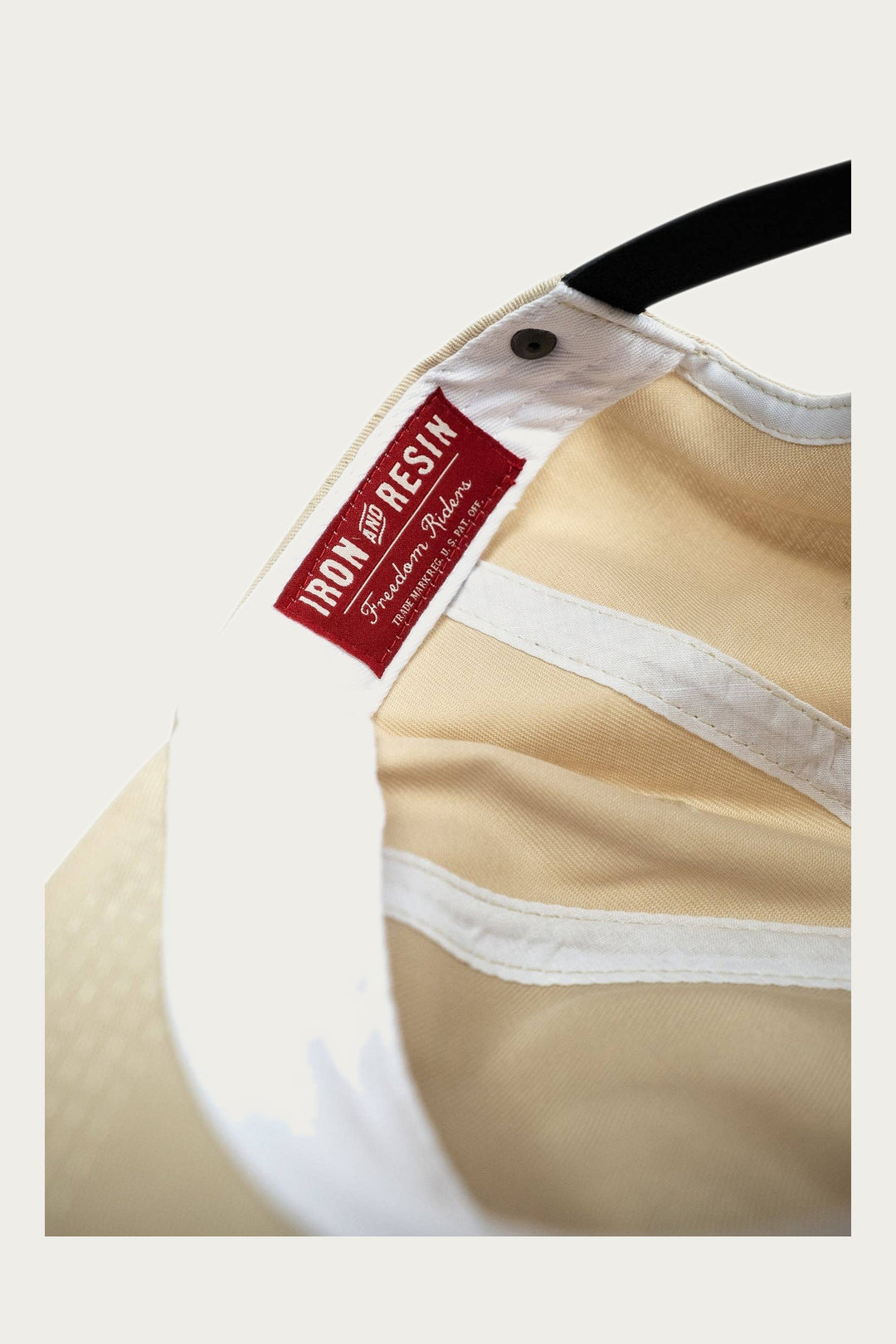Close-up of the inside of the Iron & Resin Good Luck Hat in Tan, featuring a red and white Iron & Resin label stitched onto the inner band. This adjustable snapback offers classic style and comfort for daily wear.