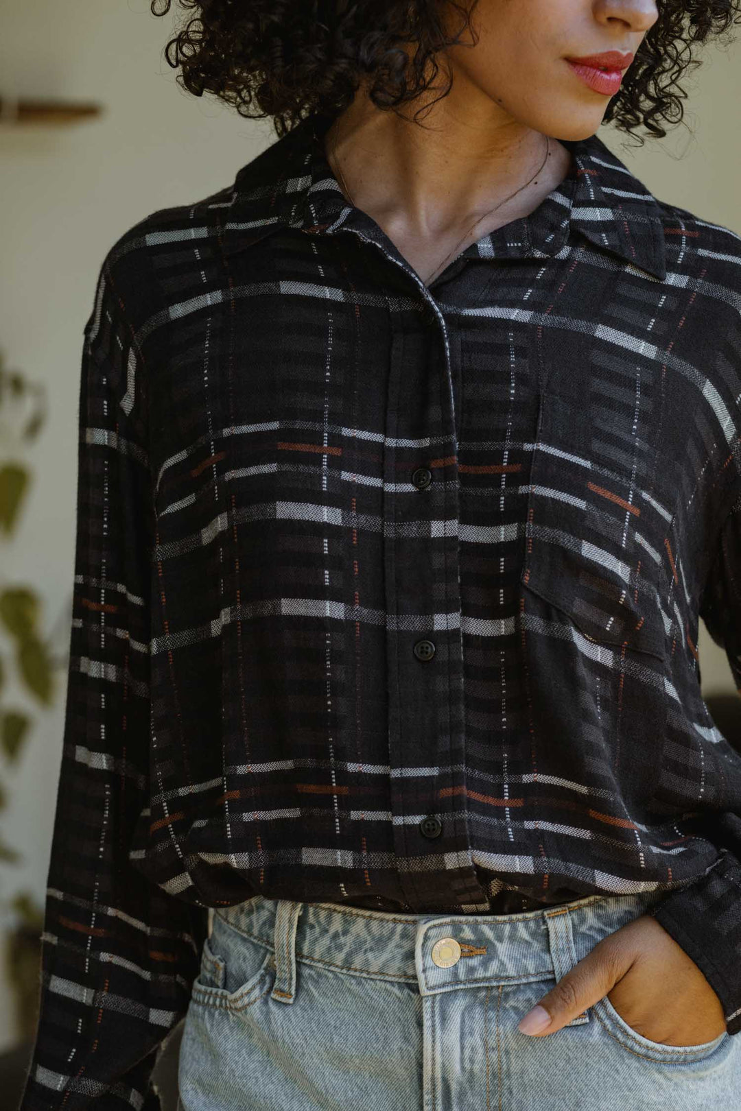 A person wears a relaxed fit, Bridge & Burn Haley Shirt in Nightfall Stripe, tucked into light blue high-waisted jeans with one hand in their pocket. Only the lower face and torso are visible.