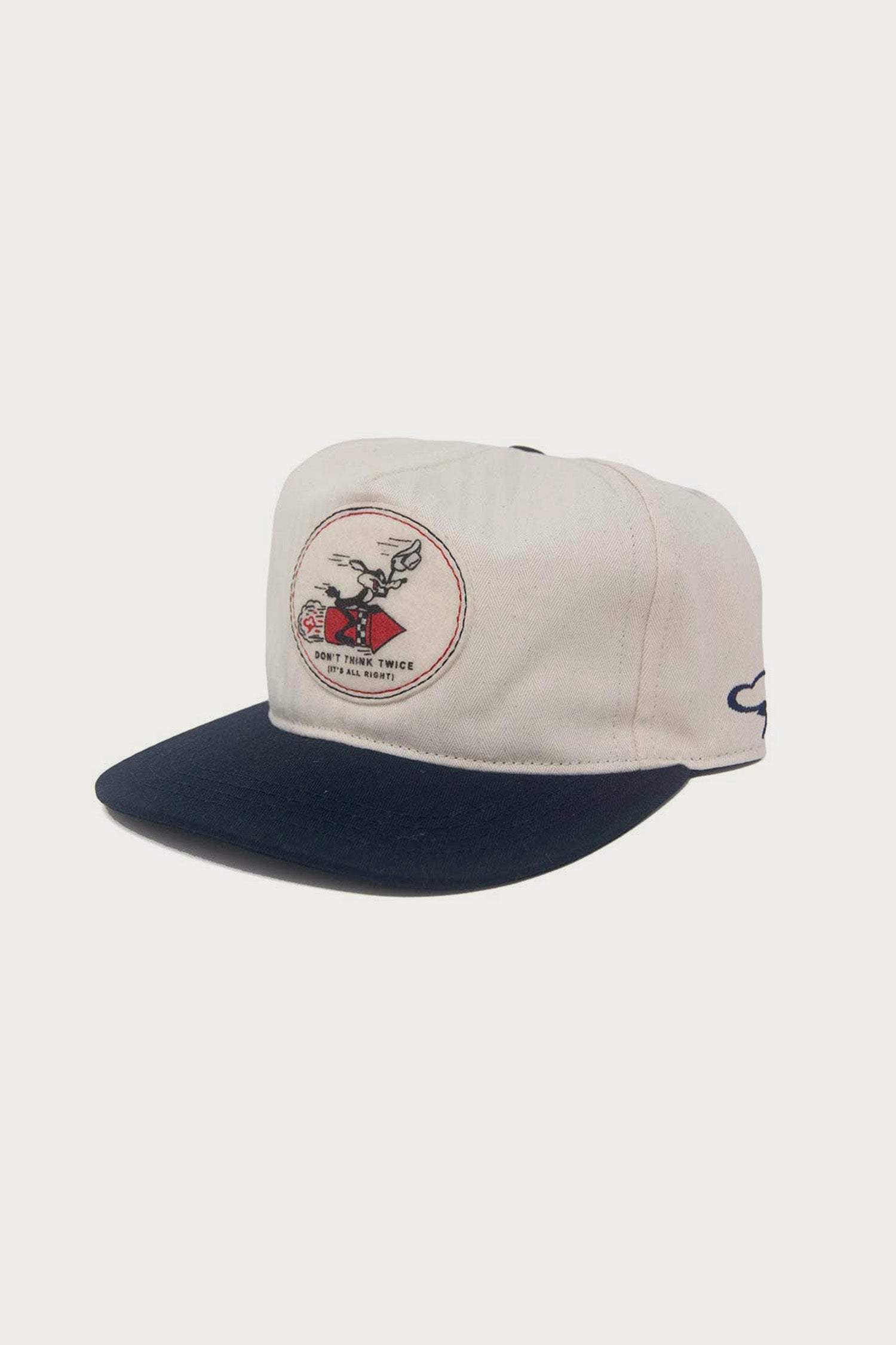 The Ampal Creative - Don't Think Twice Snapback / Navy features a white crown, navy brim, rodeo bull/rider Ampal patch with "Ride This Twice, Not Far Right" text (a nod to Bob Dylan), and a small blue logo on the side.