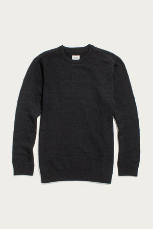 The Bridge & Burn Calder Sweater in Midnight, a black long-sleeve crew neck made from recycled materials, is laid flat on a white background. It features a textured knit pattern with ribbed cuffs, collar, and hem.
