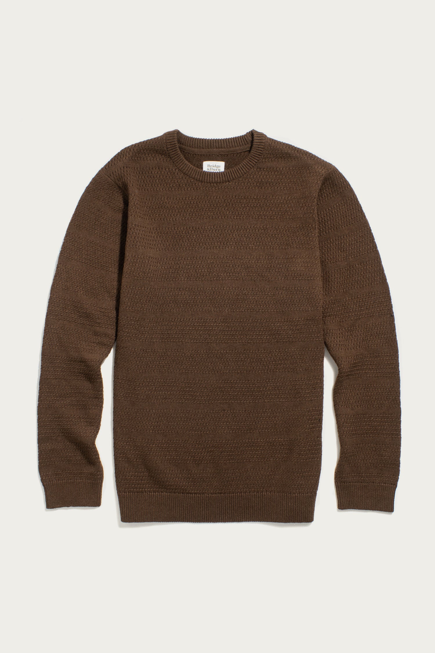 The Bridge & Burn Calder Sweater in Walnut is a brown, sustainable knit with a textured pattern, long sleeves, and ribbed cuffs, collar, and hem, shown laid flat on a white background.