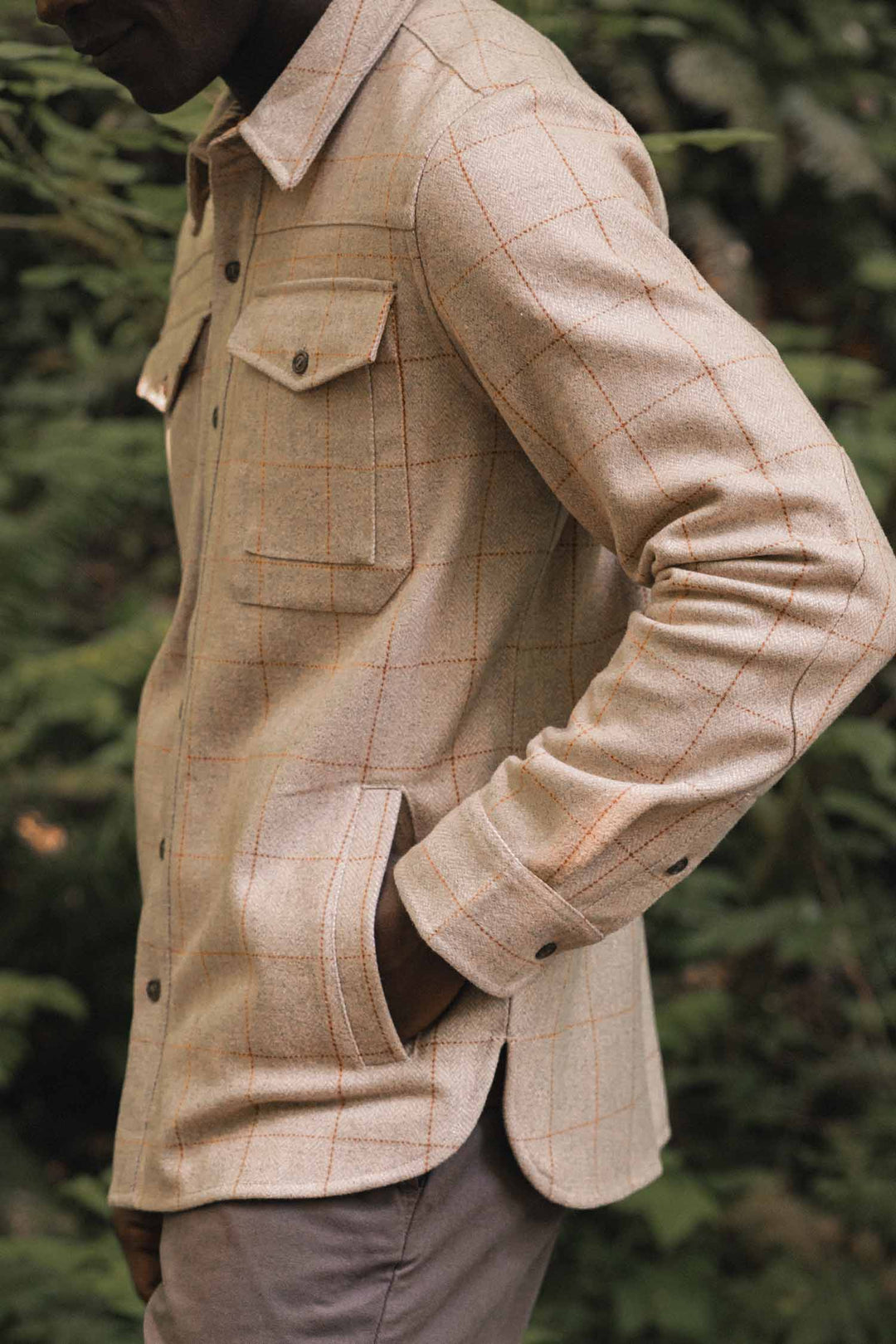 A person wearing the Bridge & Burn Fielding Shirt Jacket in Stonecross stands outdoors with one hand in their pocket, surrounded by greenery.