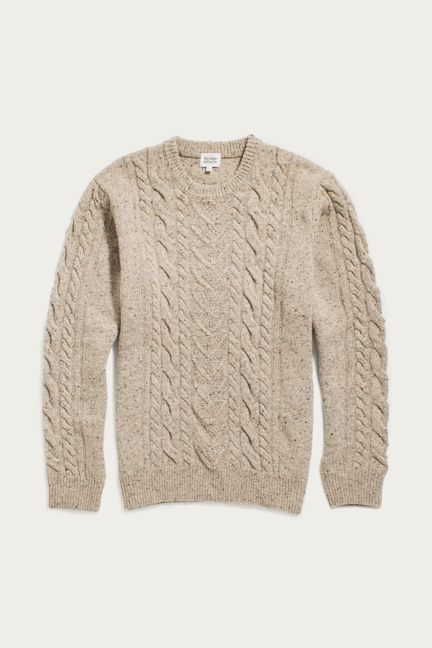 The Bridge & Burn Ludlow Sweater in Flecked Oatmeal is a beige, long-sleeve cable-knit top made from RWS-certified wool, featuring a crew neckline with ribbed cuffs and hem, shown on a white background.
