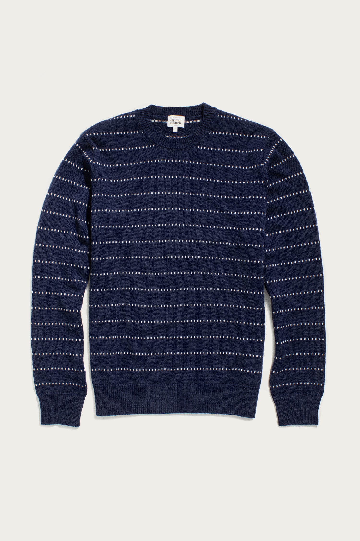 The Orson Sweater in Navy Dotted Path by Bridge & Burn is a lightweight merino wool crewneck with long sleeves and thin white dashed lines forming a subtle pattern, displayed flat on a white background.
