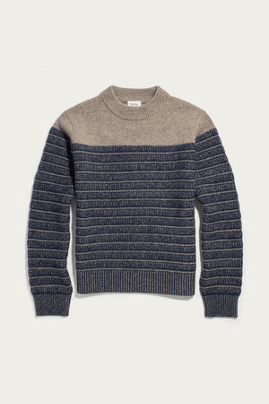 The Bridge & Burn Sabine Sweater in Mariner Stripe is a heavyweight merino wool sweater with a beige top and dark blue bottom, accented by horizontal textured stripes and finished with ribbed cuffs, hem, and a mock neck collar; shown laid flat on a white background.