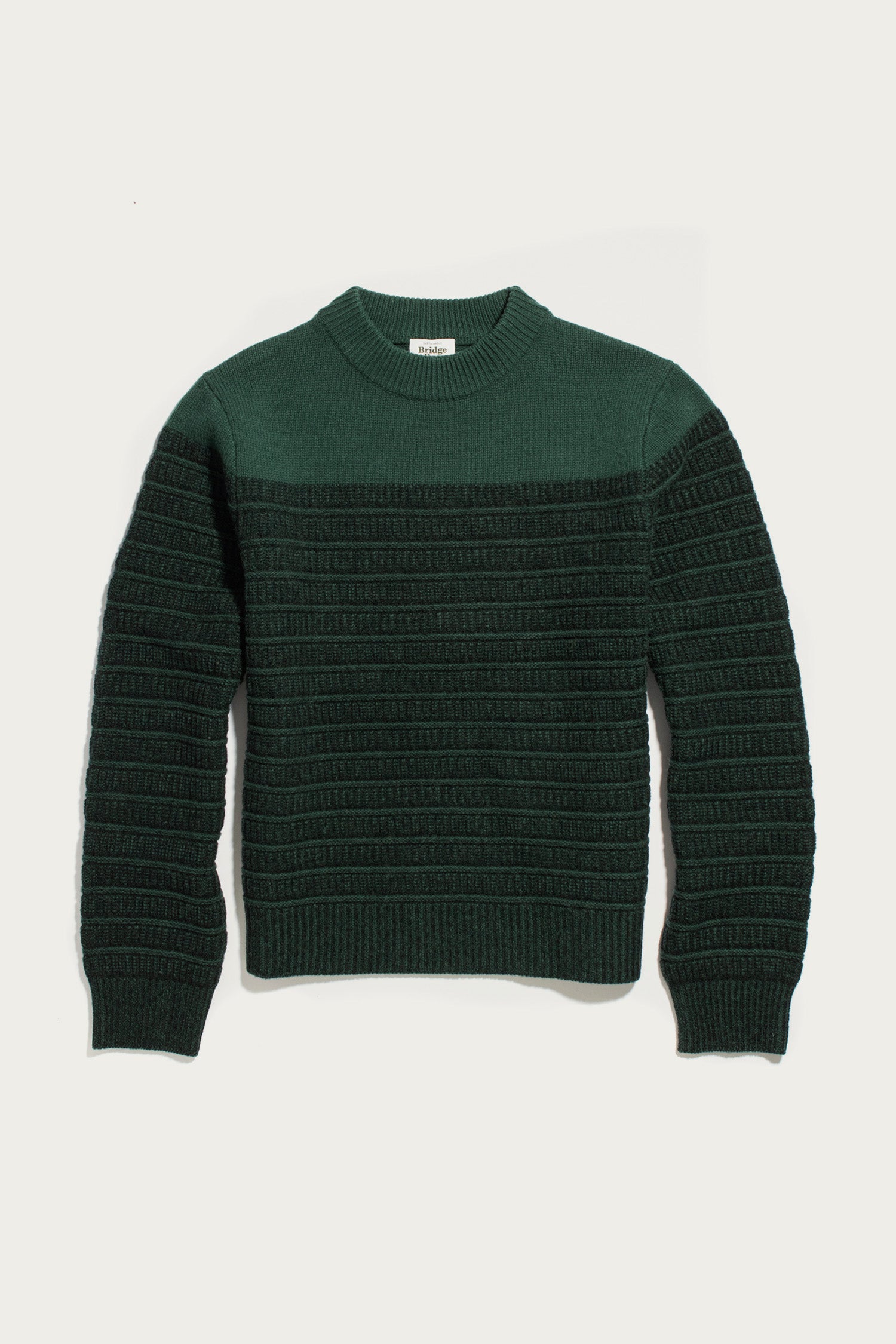 The Sabine Sweater in Pine Shadow by Bridge & Burn, a heavyweight merino wool knit with a ribbed texture and crew neckline, is shown laid flat on a white background.