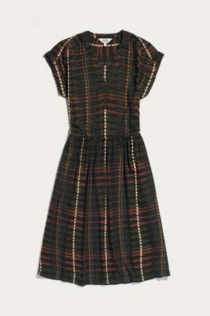 The Bridge & Burn Ira Dress in Olive Stripe is a short-sleeve, knee-length pullover dress with a dark multicolored striped pattern, featuring a gathered waist and split neckline. Crafted from a soft modal-linen blend, it is shown laid flat on a white background.