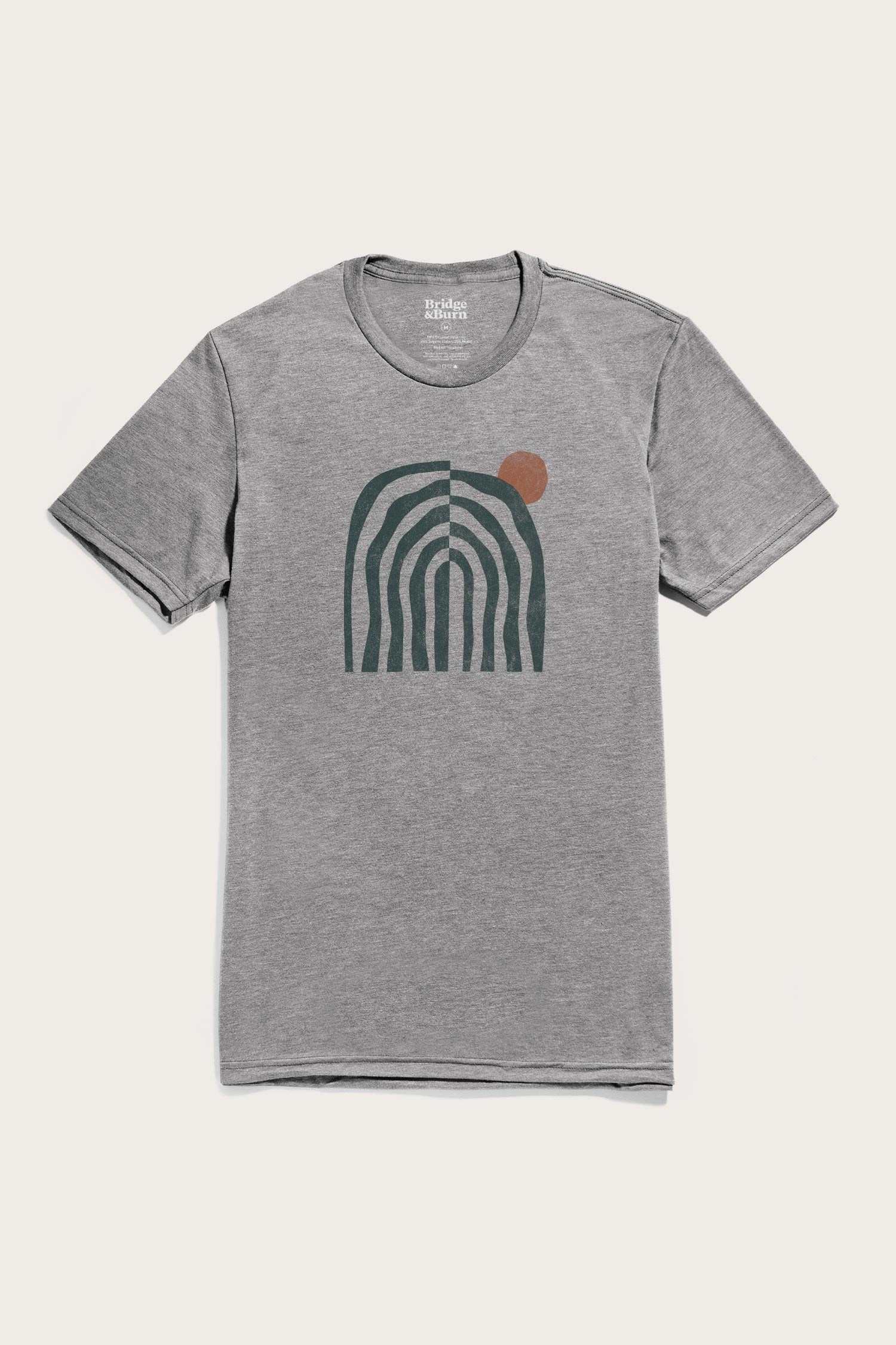 Bridge & Burn’s Men’s Canopy Tee in heather gray organic cotton features an abstract design of dark green curved lines forming an arch, with a small rust-colored circle near the top right.