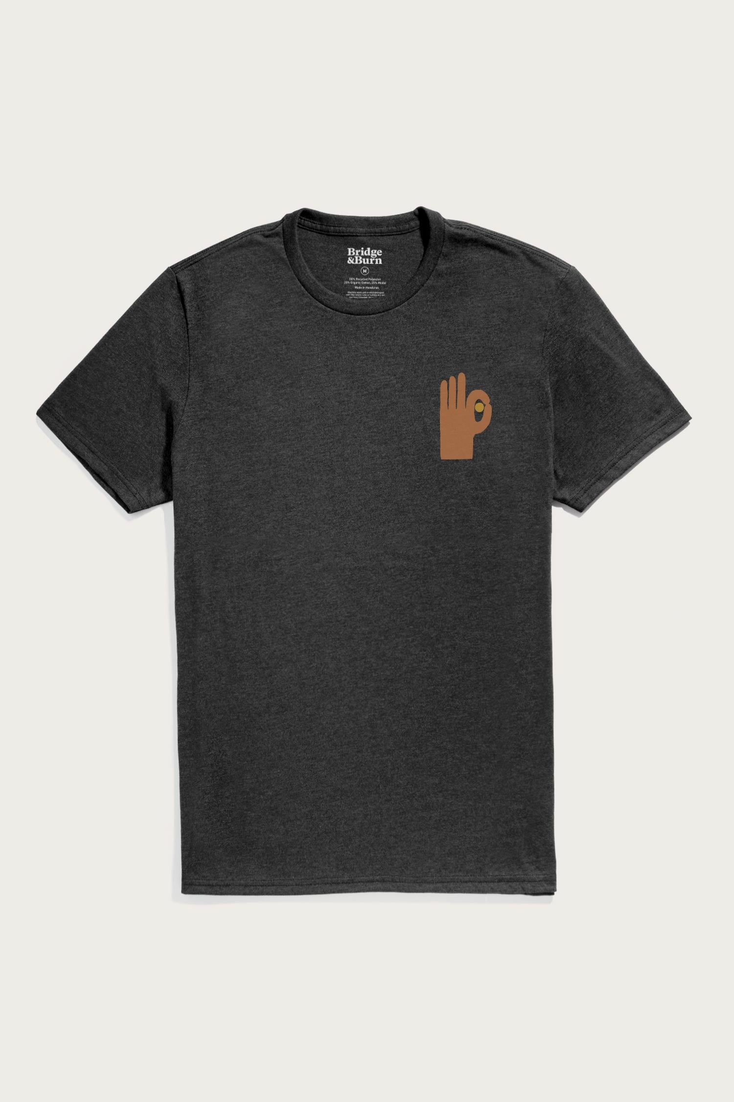 The Men's Hand Eye Tee in Black by Bridge & Burn is a lightweight shirt made from organic cotton and recycled plastic, featuring a plain black design with a small brown hand making an OK sign on the left chest.
