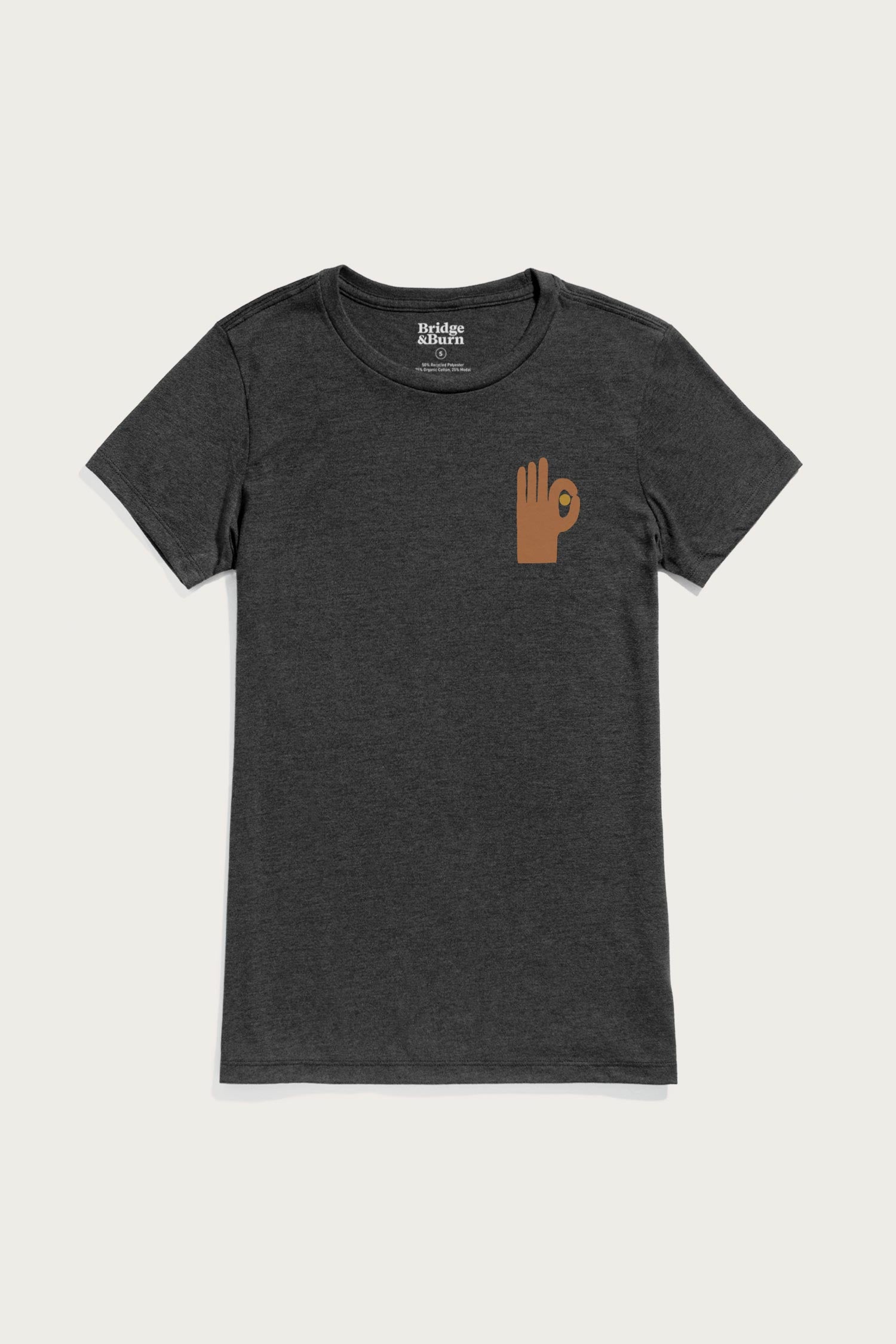 The Bridge & Burn Women's Hand Eye Tee in black is a soft organic cotton shirt featuring a small brown hand making an "OK" gesture graphic on the left chest, shown against a plain light background.