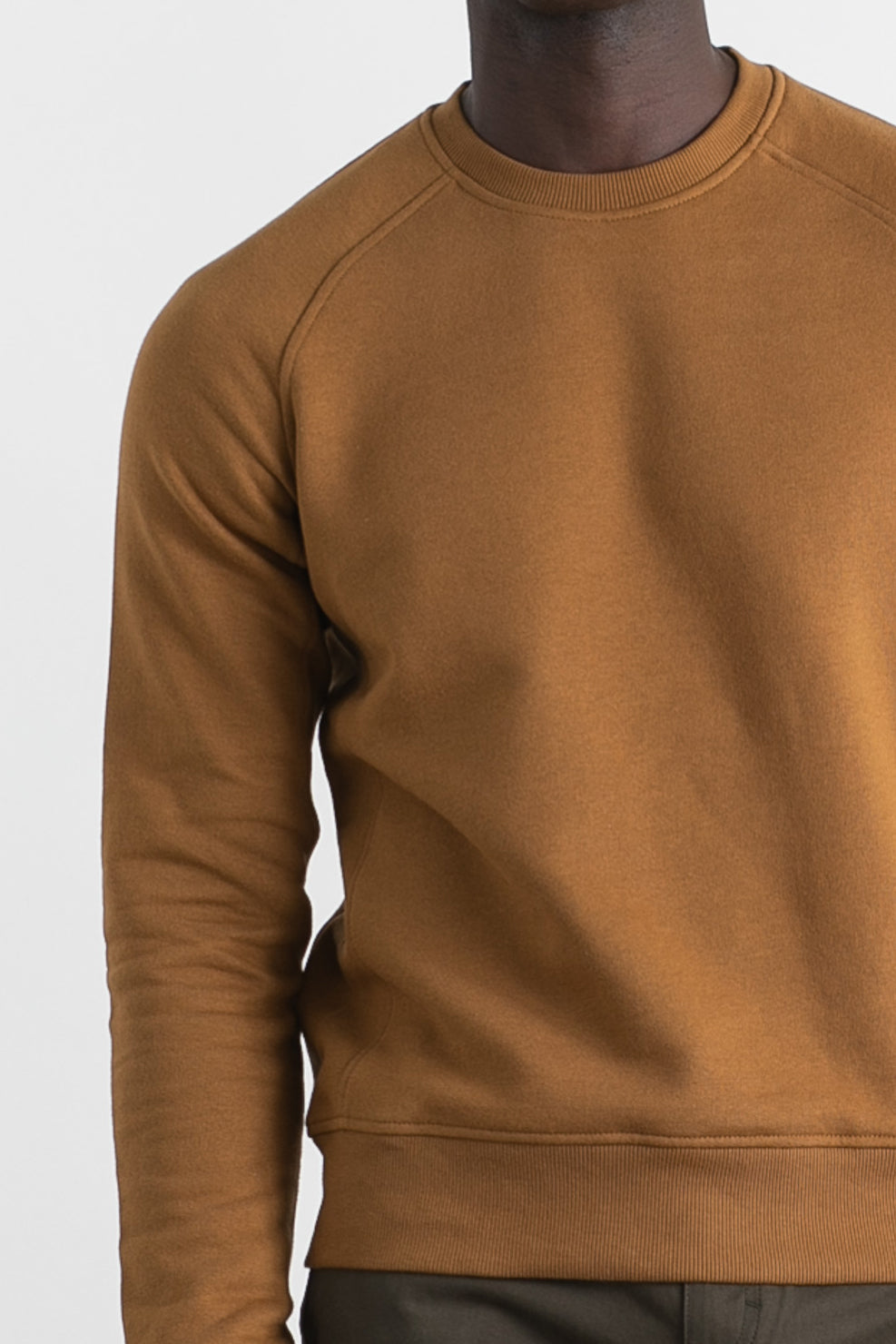 A person wearing the Bridge & Burn Fremont Crew Sweatshirt in Bronze with dark pants, shown from shoulders to hips against a plain light background.