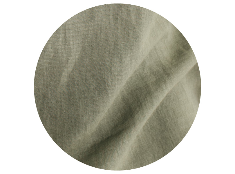 Close-up view of a piece of light olive green fabric, showing its texture, slight wrinkles, and fine weave pattern.