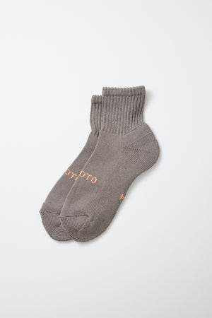 A pair of RoToTo Everyday Pile Ankle Socks in dark gray, crafted from organic cotton with ribbed cuffs and small orange text on the sides, made in Japan and displayed on a plain white background.
