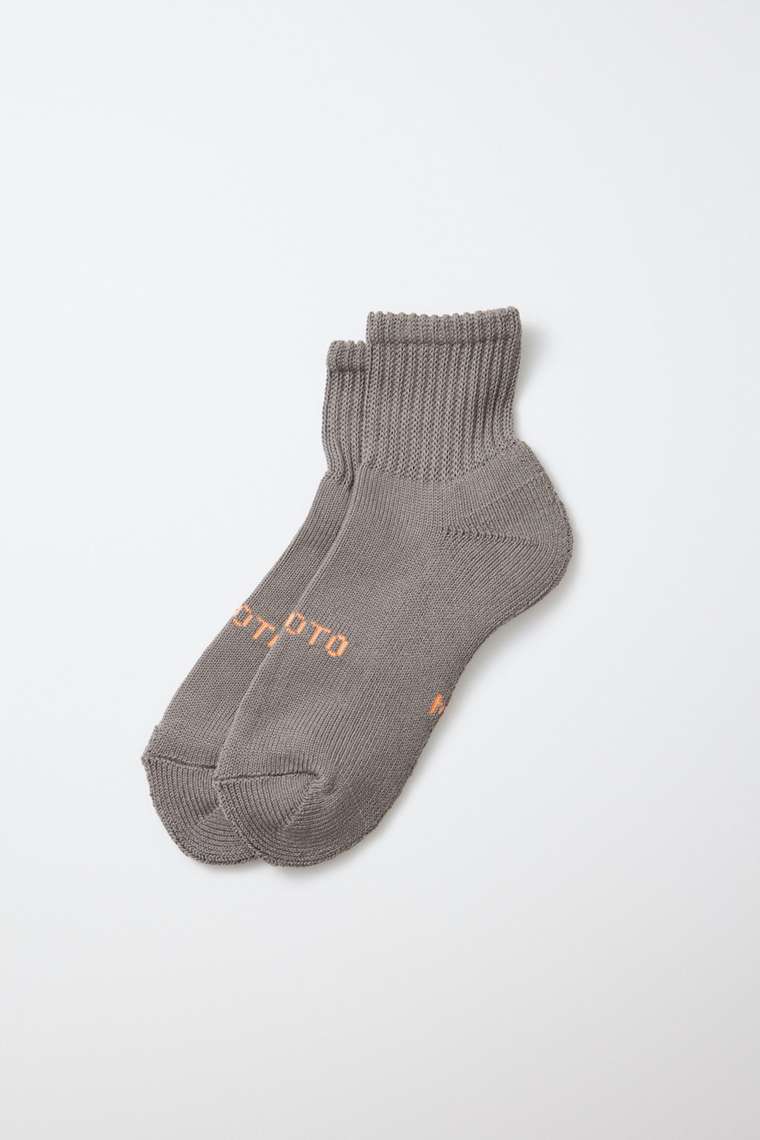 A pair of RoToTo Everyday Pile Ankle Socks in dark gray, made in Japan with ribbed cuffs and subtle orange text on the sides by RoToTo, displayed on a plain white background.