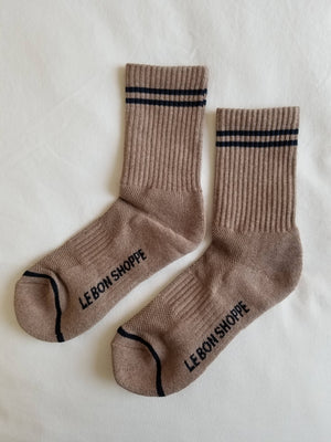 The Le Bon Shoppe Boyfriend Socks in Cocoa feature two black stripes near the top and "LE BON SHOPPE" printed on the soles, shown here on a white surface.