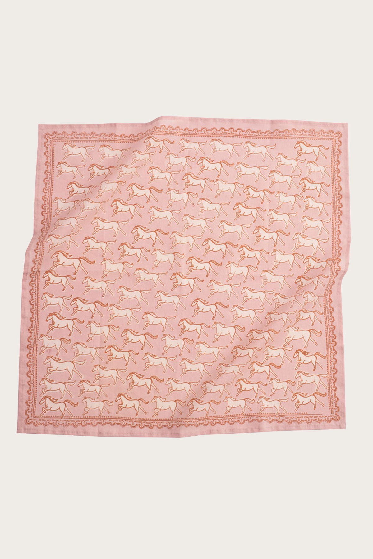 The Handker Bandanas - No. 062 Horses Bandana by Handker Bandanas is a light pink, premium cotton bandana with a repeating horse print and decorative border, shown slightly wrinkled and laid flat on a neutral background.