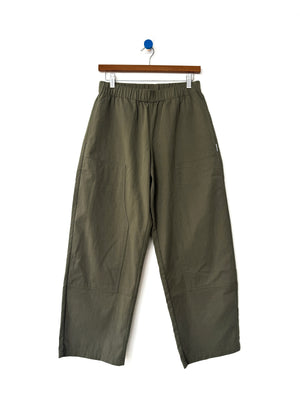 Le Bon Shoppe - Gardener’s Pant in Army Green, featuring a relaxed silhouette and spacious front pockets, crafted from lightweight cotton-nylon fabric, shown hanging on a wooden hanger against a white background.