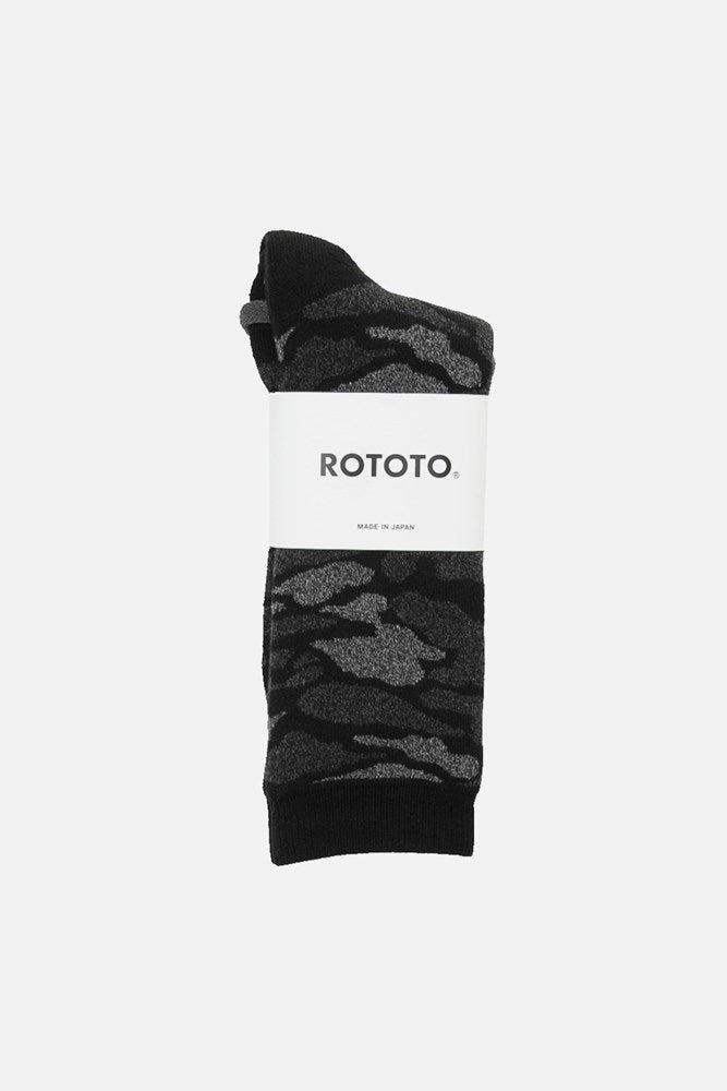 A pair of RoToTo Pile Camo Socks in black, featuring a black and gray camo pattern and wrapped with a white label showing the RoToTo brand name and MADE IN JAPAN.
