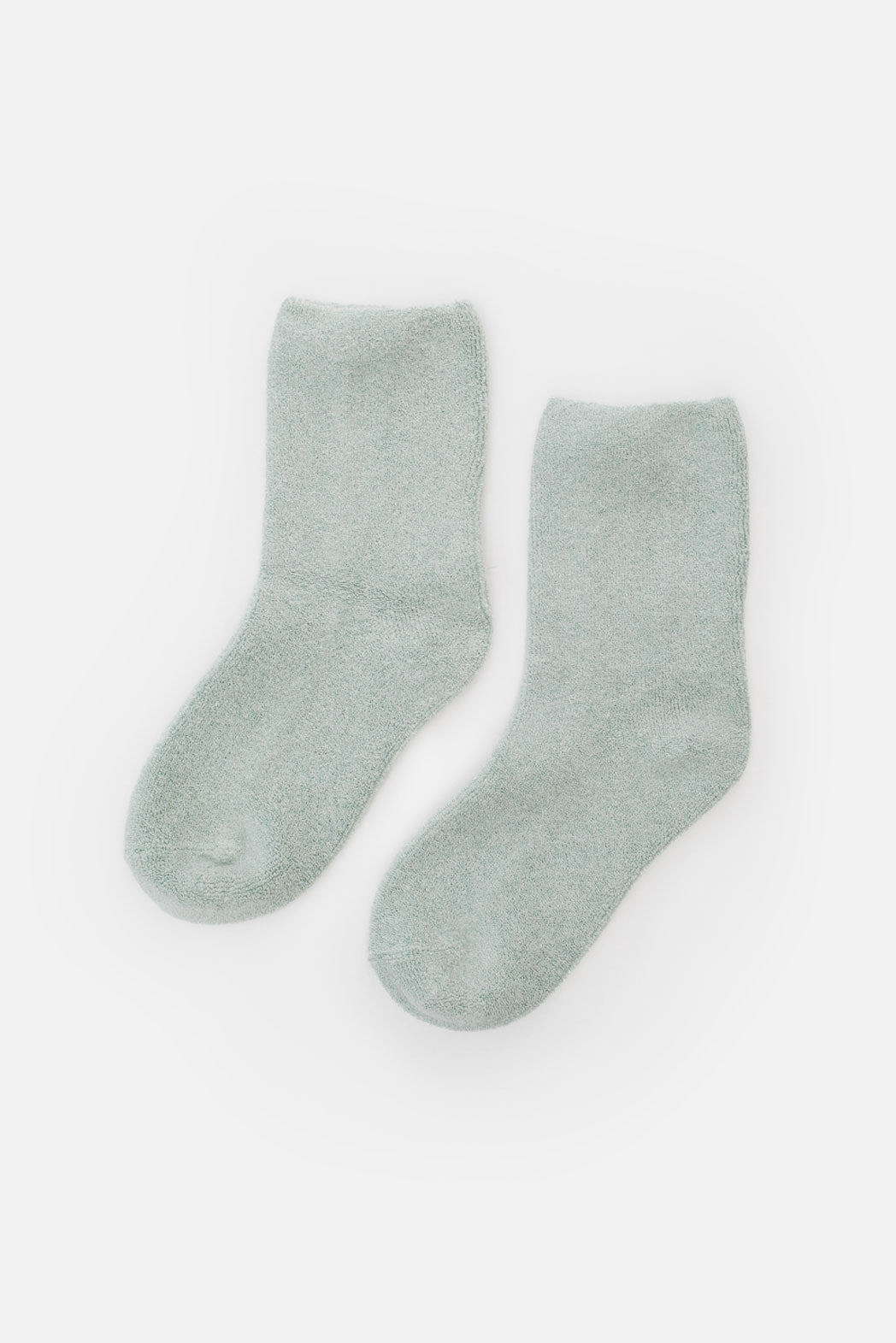 A pair of Le Bon Cloud Socks in Bay, featuring a soft texture and light gray color, are laid flat side by side on a white background.